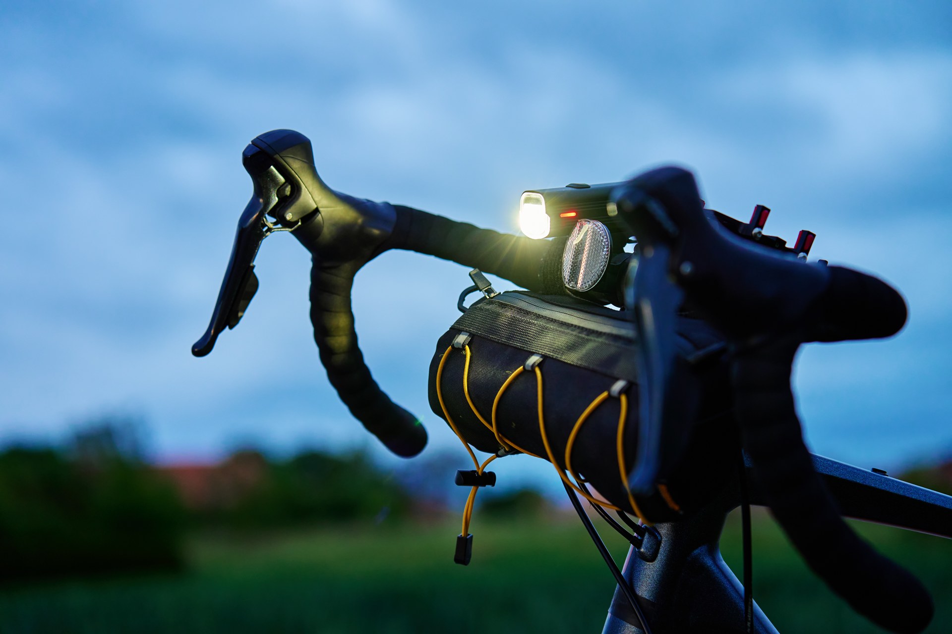 Phare de vélo éclairant un chemin de campagne à la nuit tombée